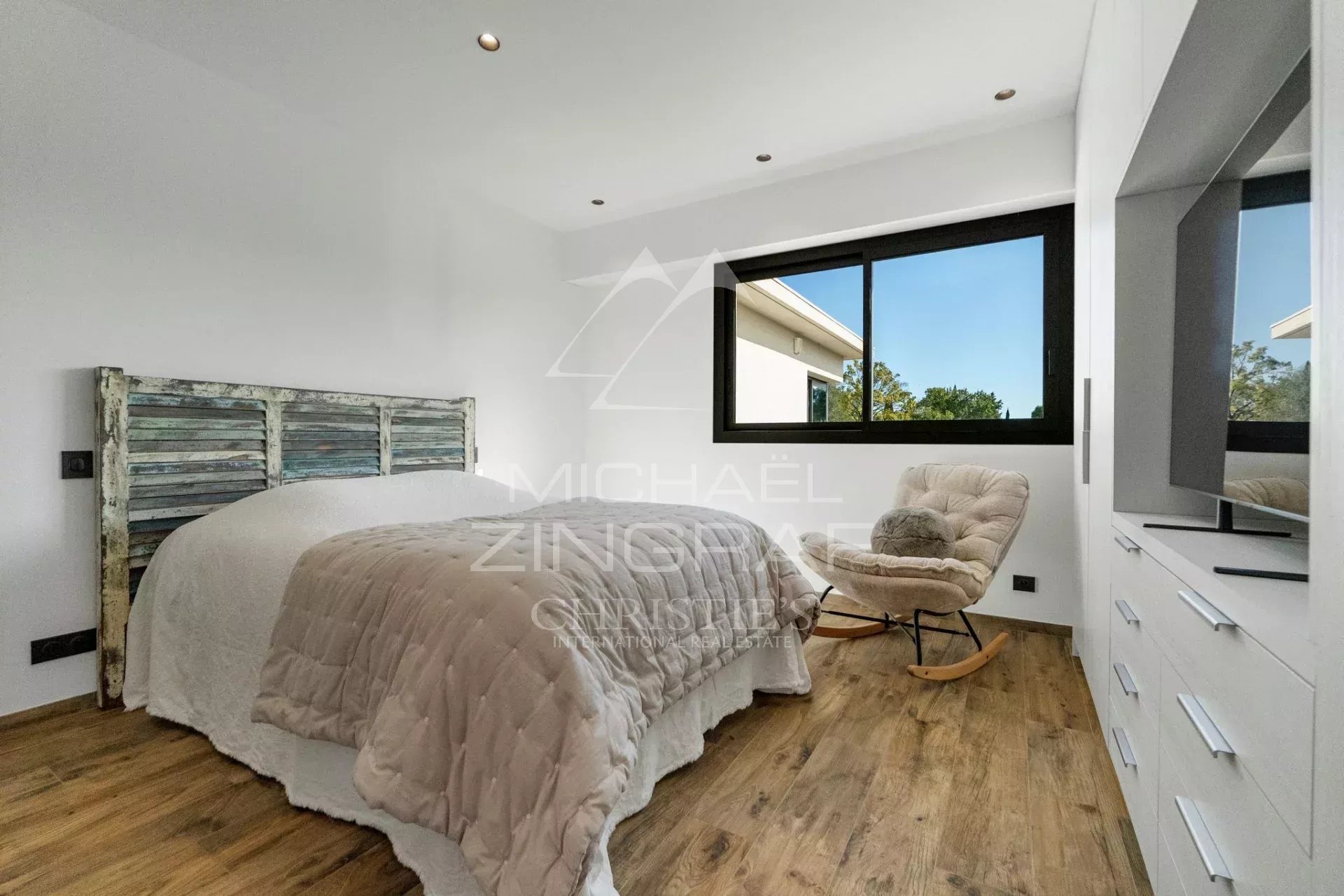 Chambre moderne avec lit et fauteuil, lumière naturelle à Mougins.