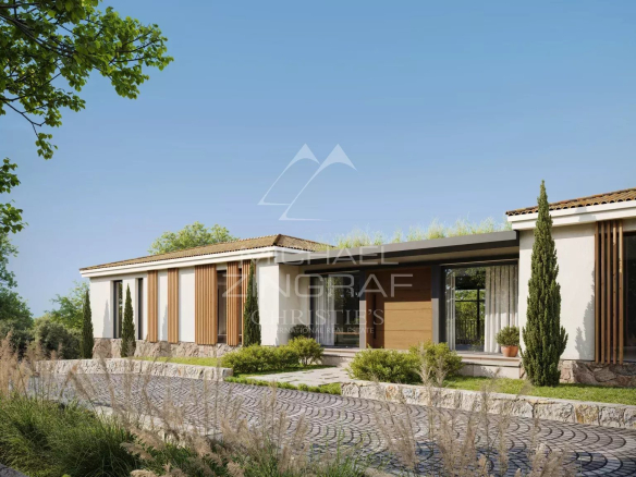 View of a modern villa on a plot of land in Mougins, with a garden and a paved driveway.