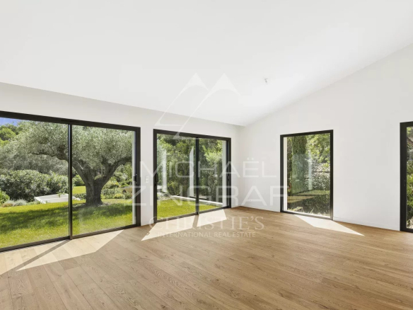Intérieur lumineux d'une villa contemporaine avec de grandes fenêtres donnant sur un jardin.