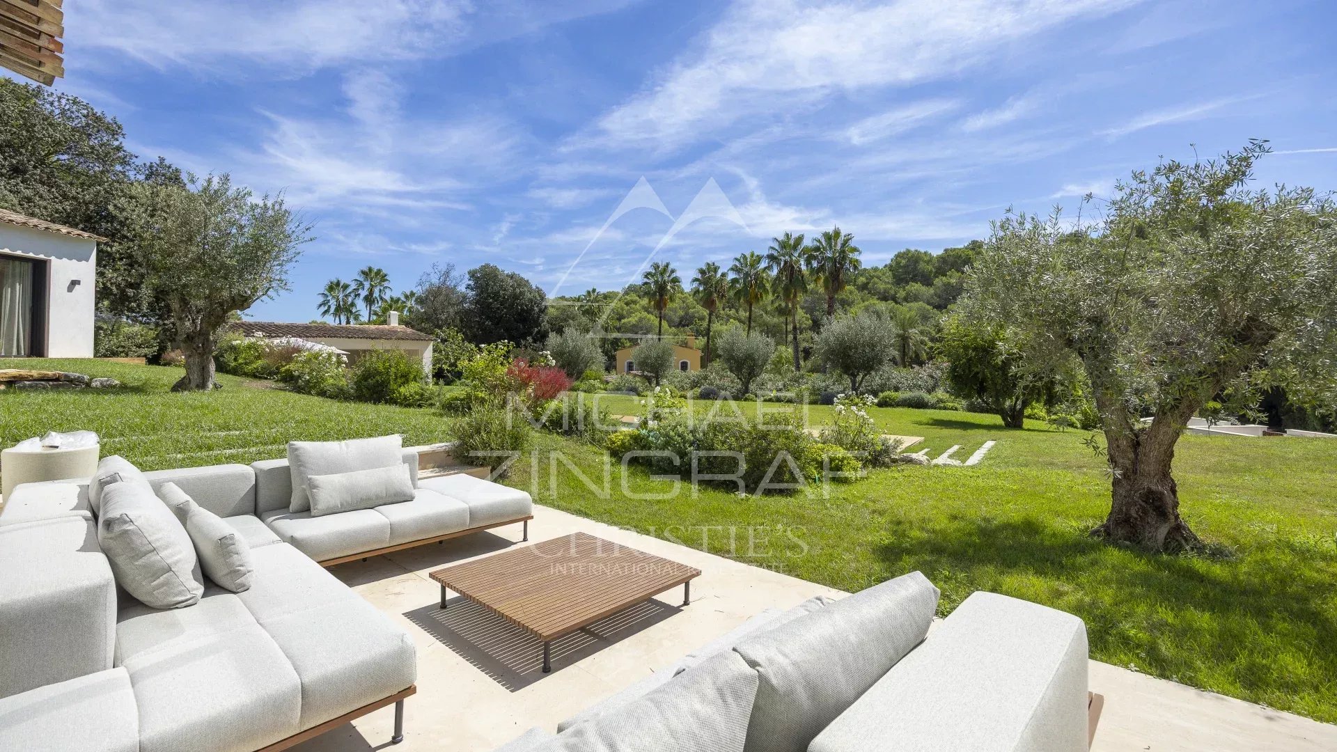Terrasse de villa contemporaine à Mougins Terrasse d'une villa contemporaine avec des canapés et une vue sur un jardin verdoyant à Mougins.