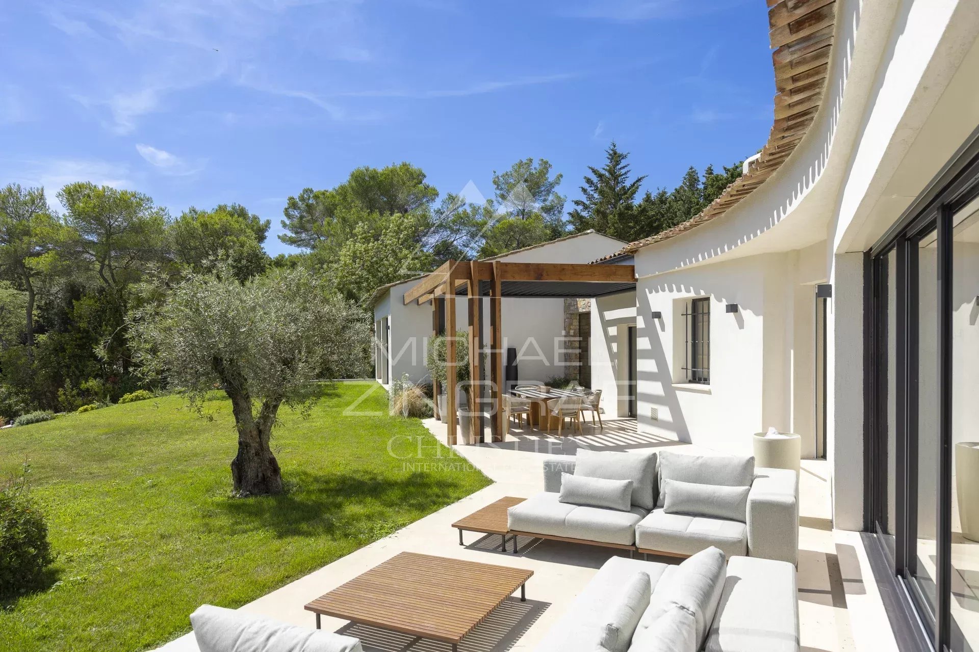 Villa provençale contemporaine à Mougins Terrasse d'une villa provençale contemporaine à Mougins avec mobilier extérieur et jardin verdoyant.