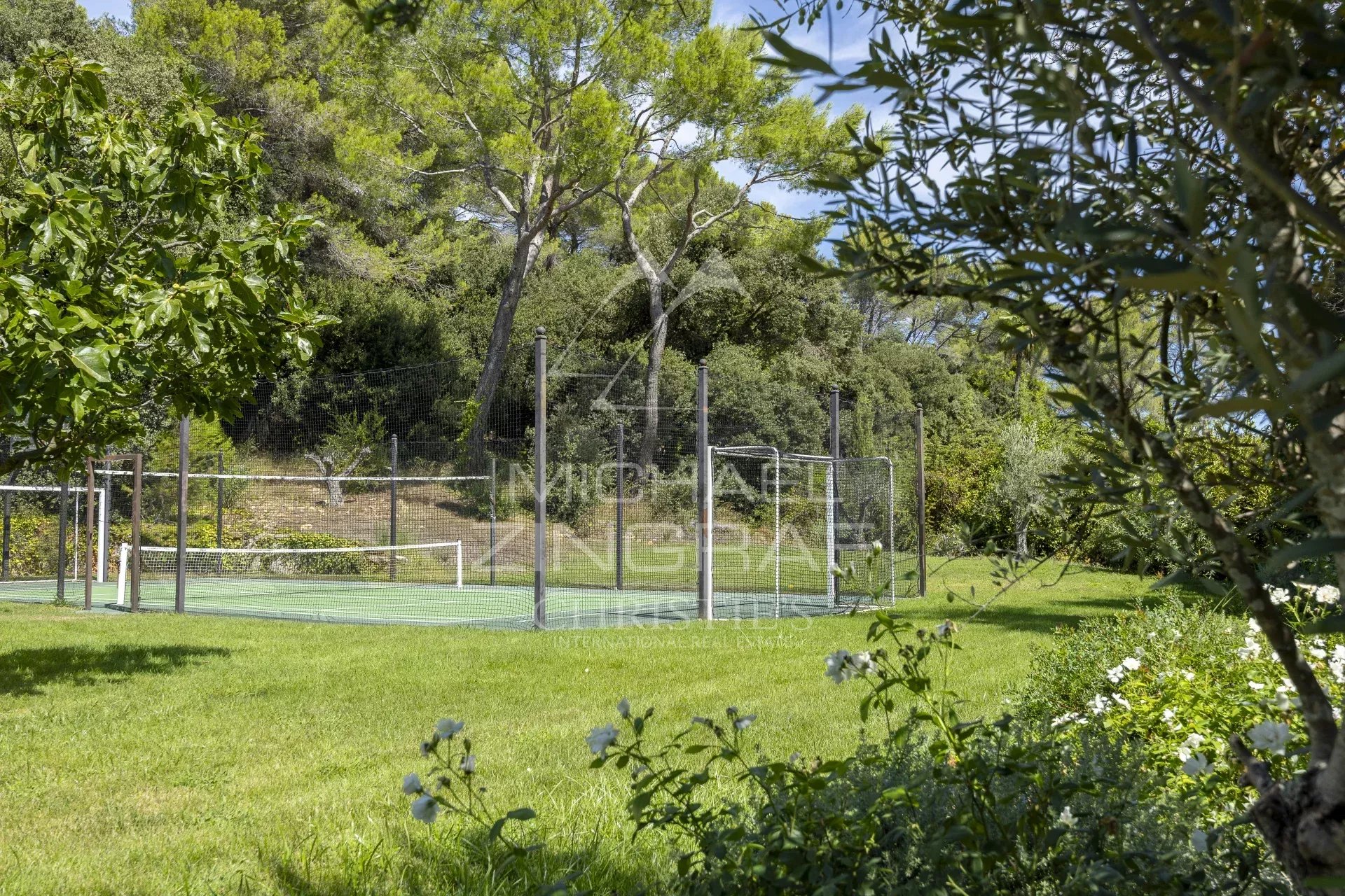 Terrains de tennis à Mougins Terrains de tennis dans un jardin verdoyant à Mougins, entouré d'arbres et de fleurs.