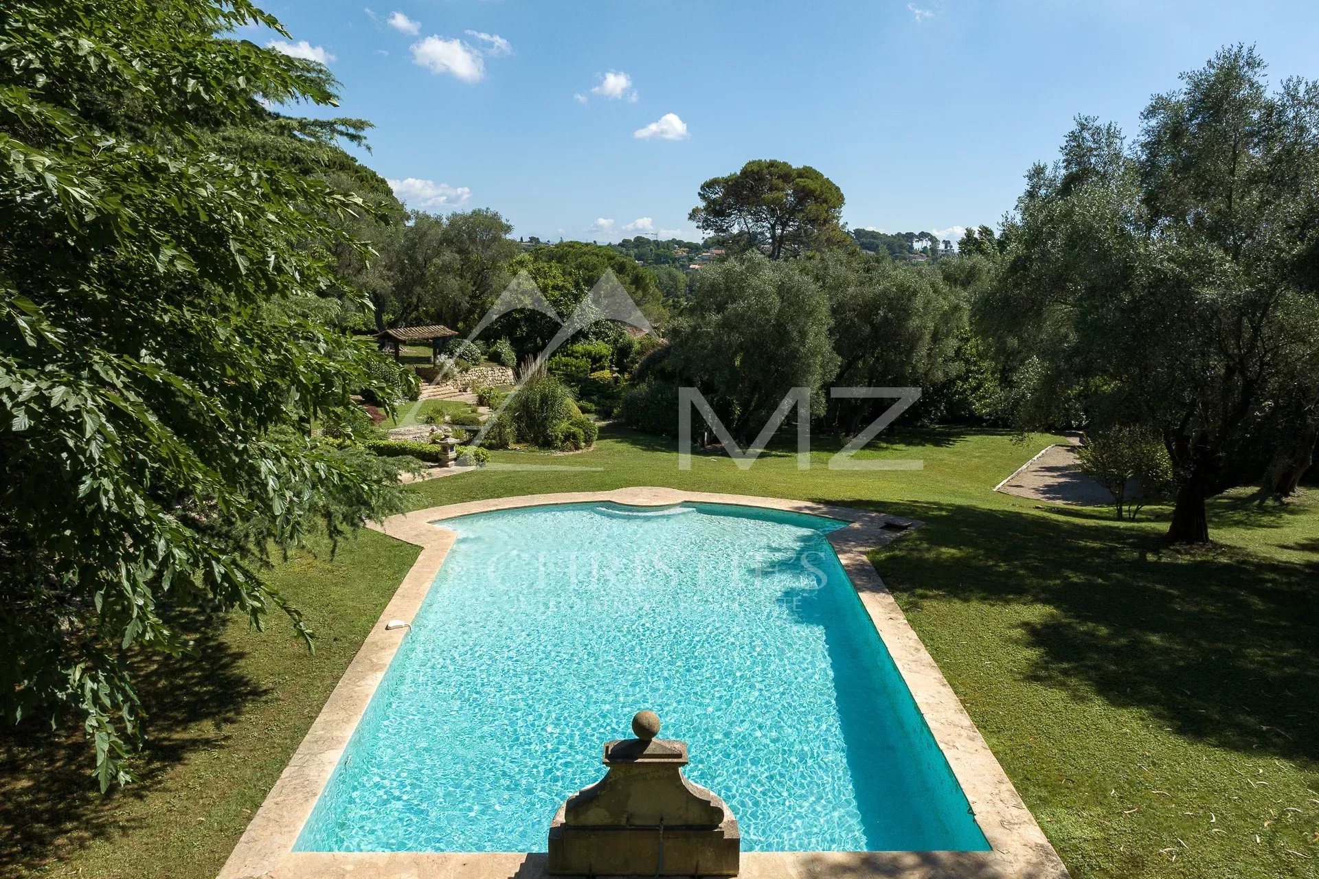 Vue d'une piscine dans un parc paysager avec des oliviers à Mougins.