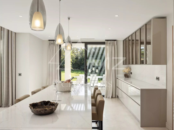 Intérieur d'une villa contemporaine avec cuisine moderne et vue sur le jardin.