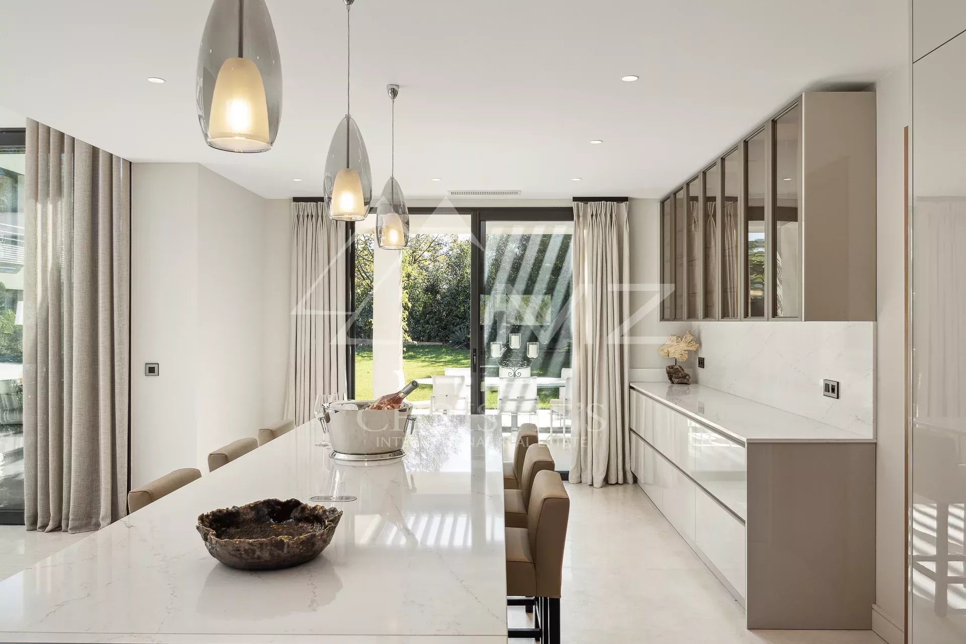 Intérieur d'une villa contemporaine avec cuisine moderne et vue sur le jardin.