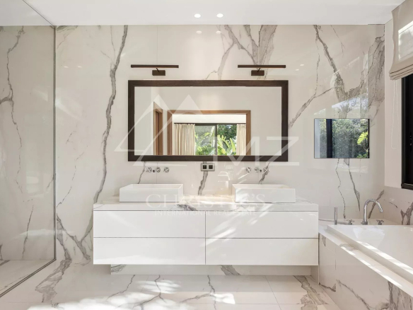 Salle de bain moderne avec double vasque et baignoire, décorée de marbre.