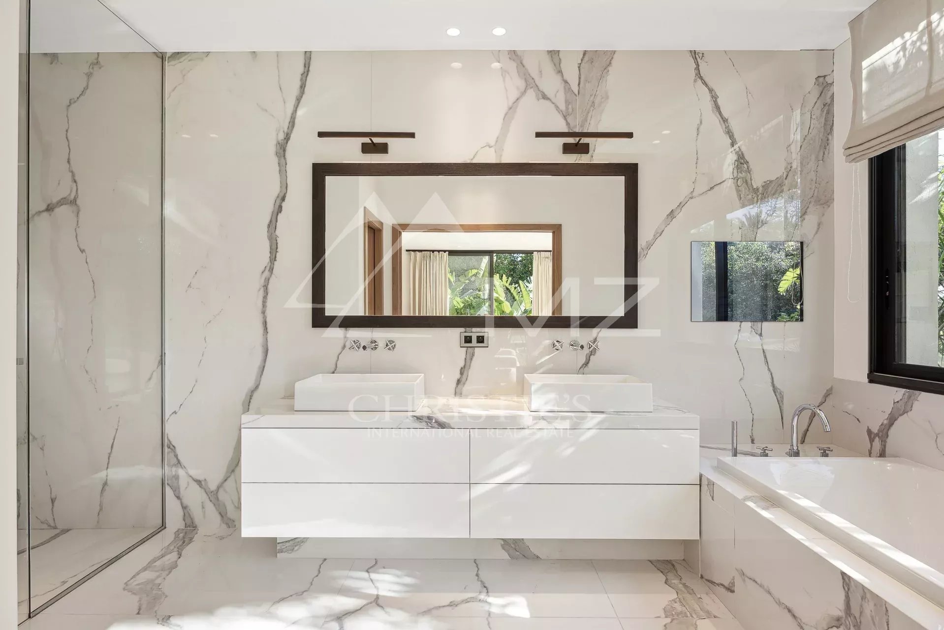 Salle de bain moderne avec double vasque et baignoire, décorée de marbre.
