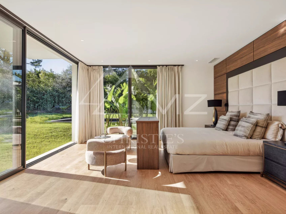 Chambre moderne avec grandes fenêtres donnant sur un jardin verdoyant.