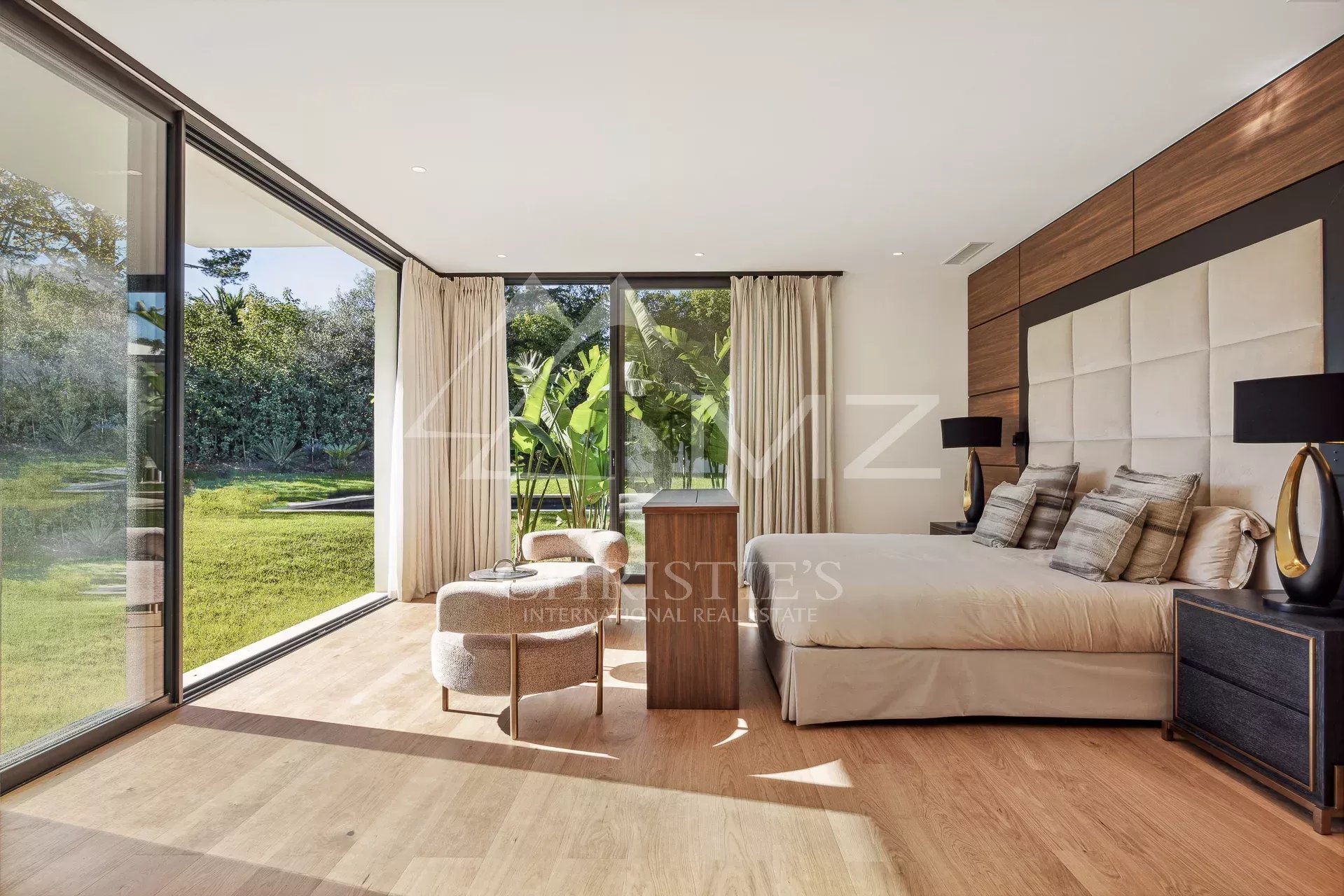 Chambre moderne avec grandes fenêtres donnant sur un jardin verdoyant.