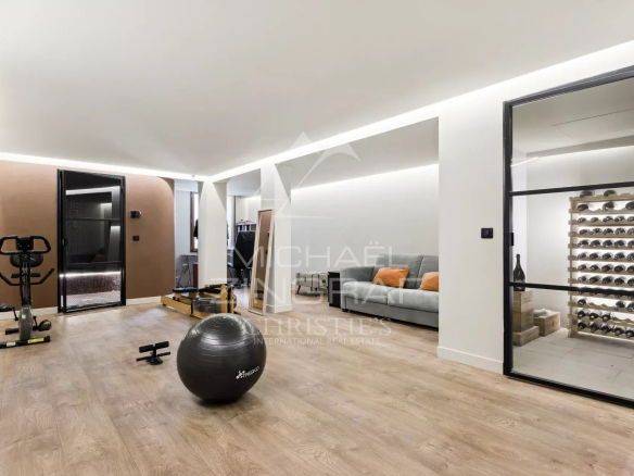 Intérieur d'une bastide rénovée avec un espace de vie moderne, incluant un coin salon et un équipement de fitness.