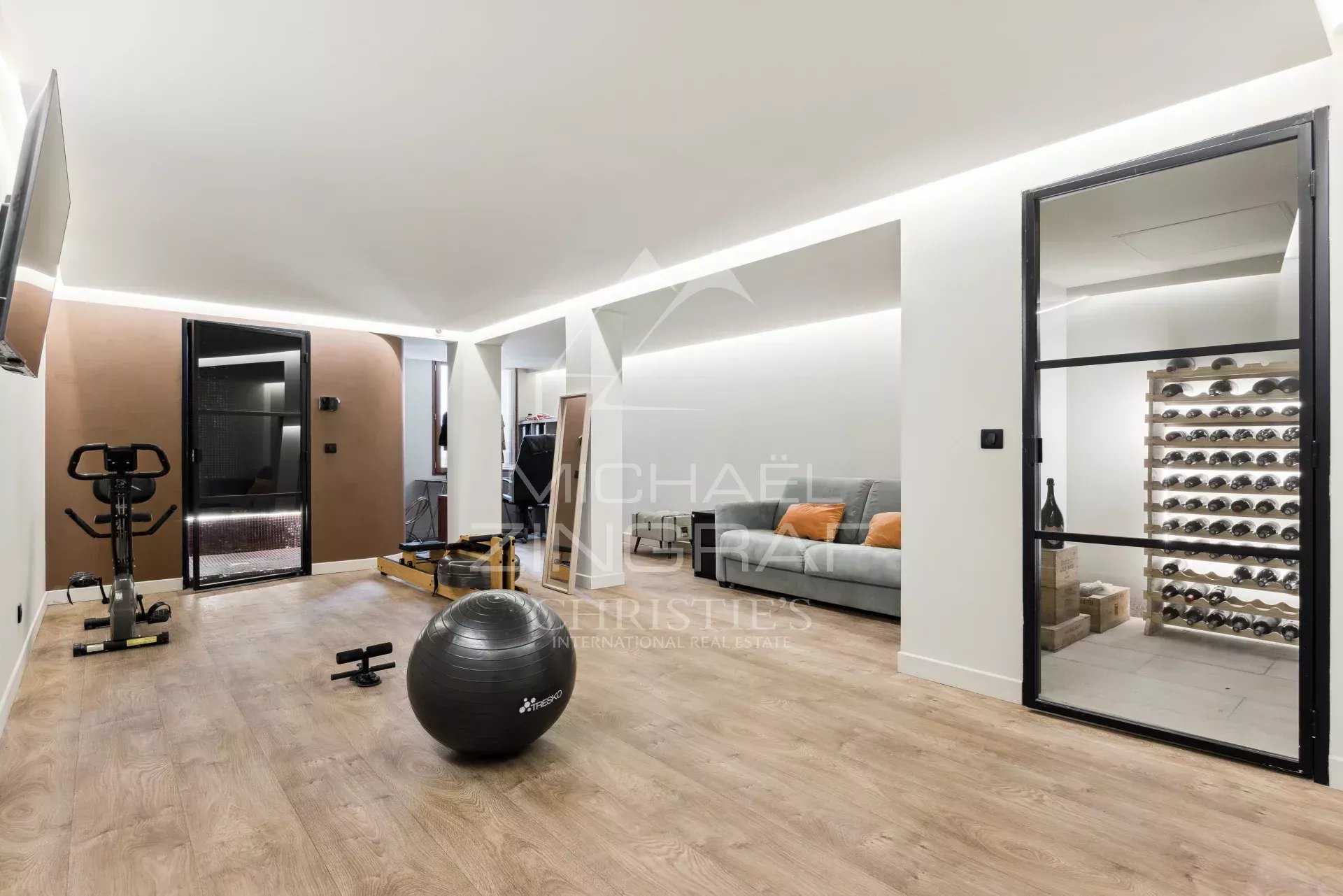 Intérieur d'une bastide rénovée avec un espace de vie moderne, incluant un coin salon et un équipement de fitness.