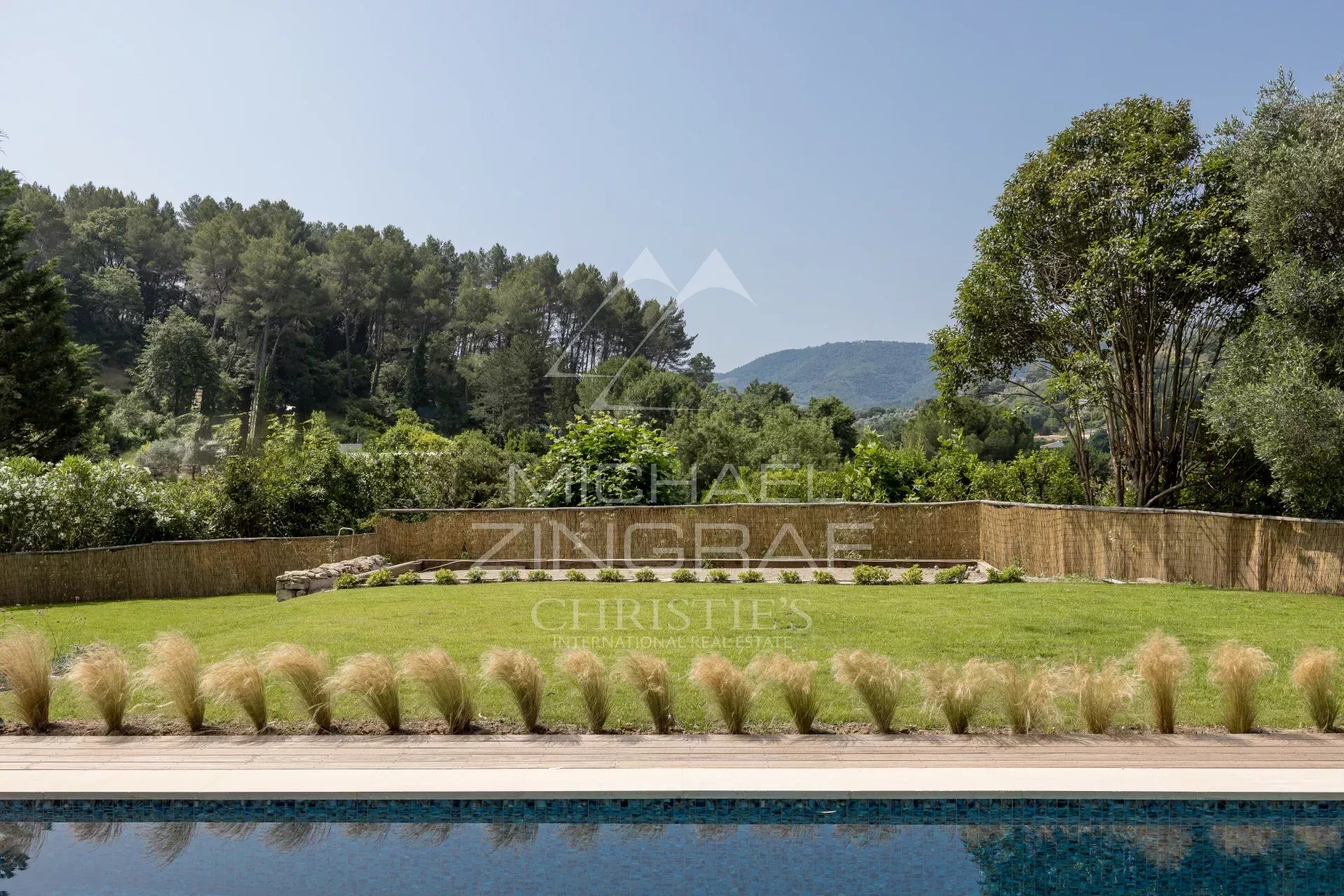 Vue d'un jardin paysager avec piscine, entouré d'arbres et de collines à Pégomas.