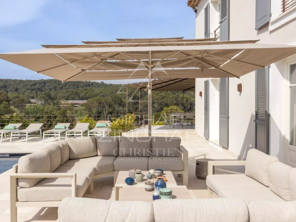 Terrace of a renovated villa with garden furniture and parasol, overlooking nature in Mougins.