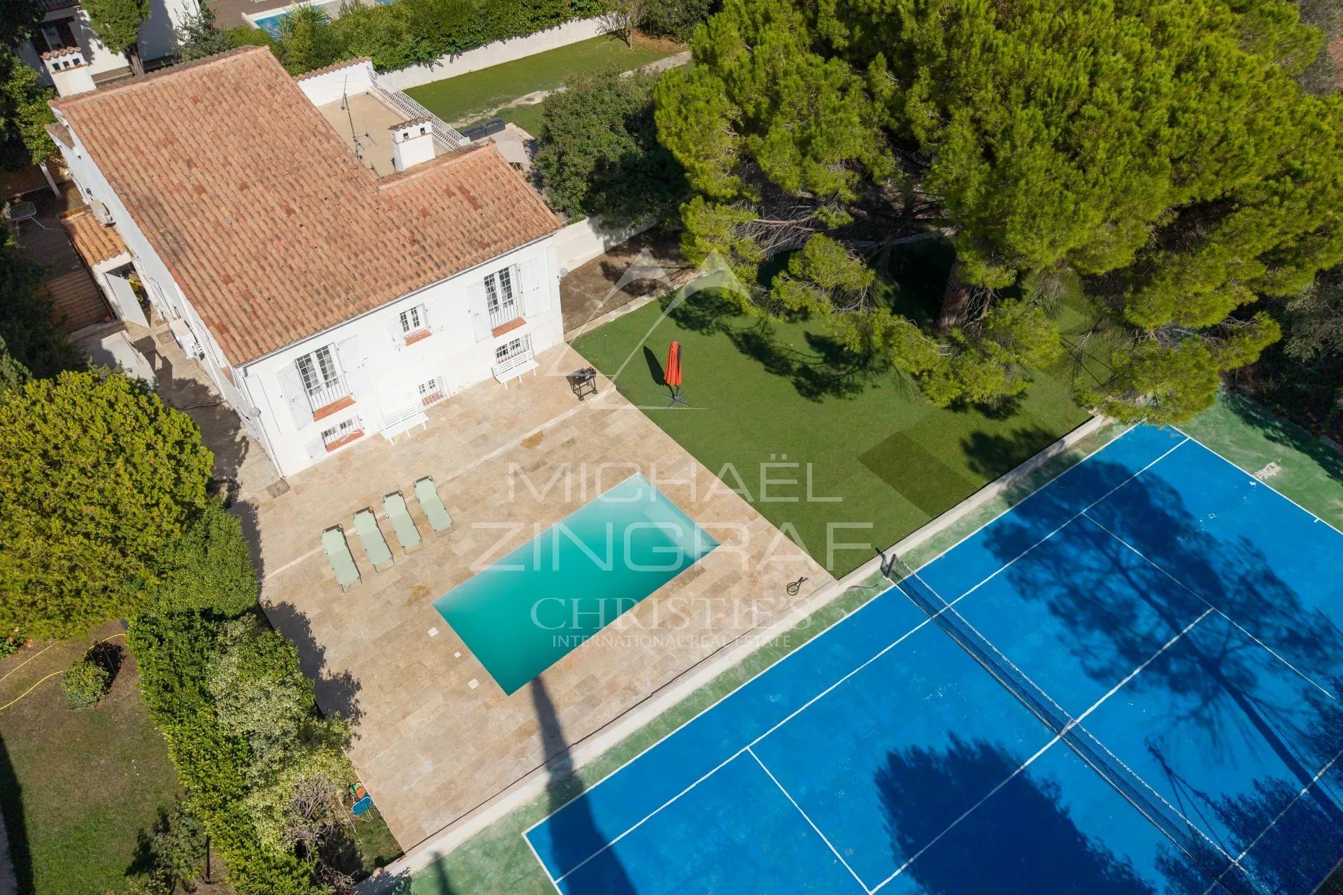 Villa familiale avec piscine et court de tennis à Mougins Vue aérienne d'une villa avec piscine et court de tennis à Mougins, entourée d'arbres.