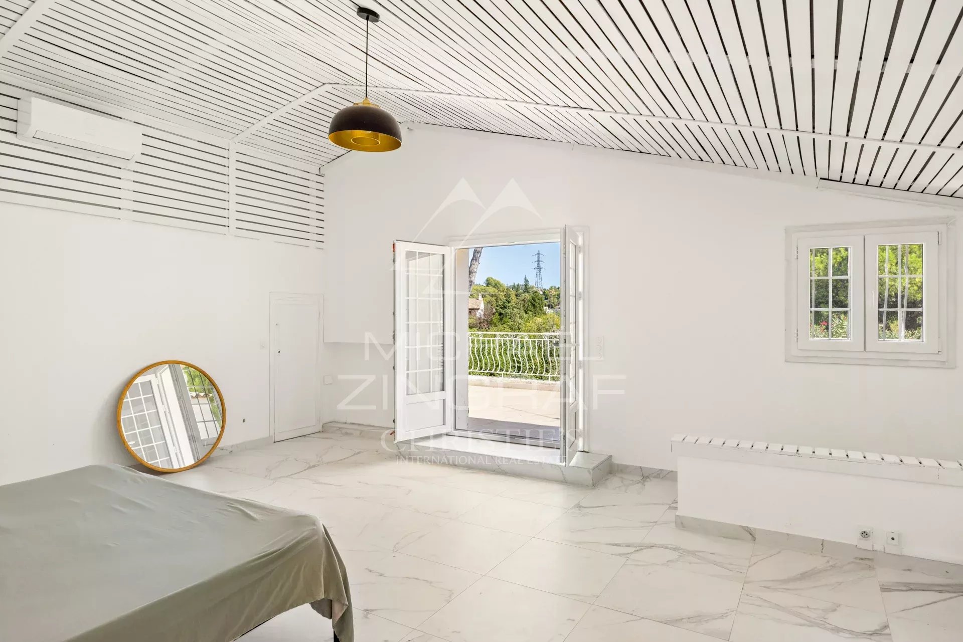 Chambre de villa à Mougins Chambre spacieuse avec fenêtres ouvertes et miroir, dans une villa à Mougins.
