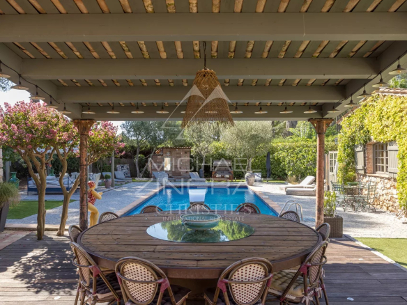 Terrasse couverte avec table en bois et piscine à Mouans-Sartoux.