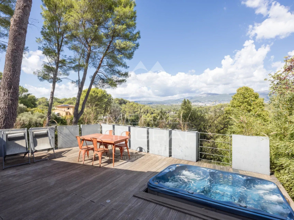 Terrasse en bois avec jacuzzi et table, vue sur la nature à Mouans-Sartoux.