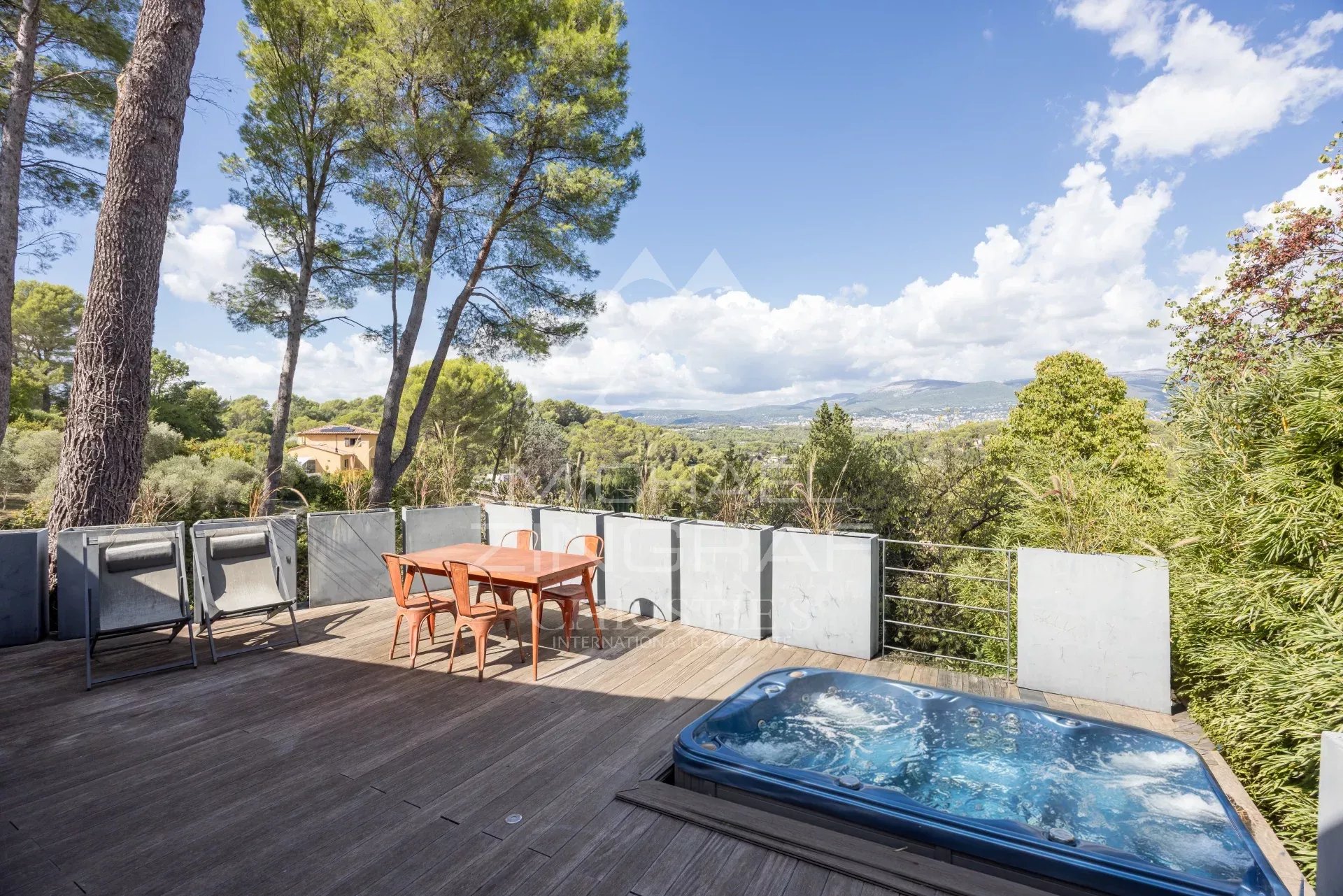 Terrasse avec jacuzzi à Mouans-Sartoux Terrasse en bois avec jacuzzi et table, vue sur la nature à Mouans-Sartoux.