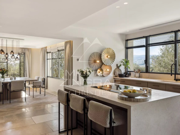 Intérieur d'une villa moderne avec cuisine ouverte et vue sur la verdure.