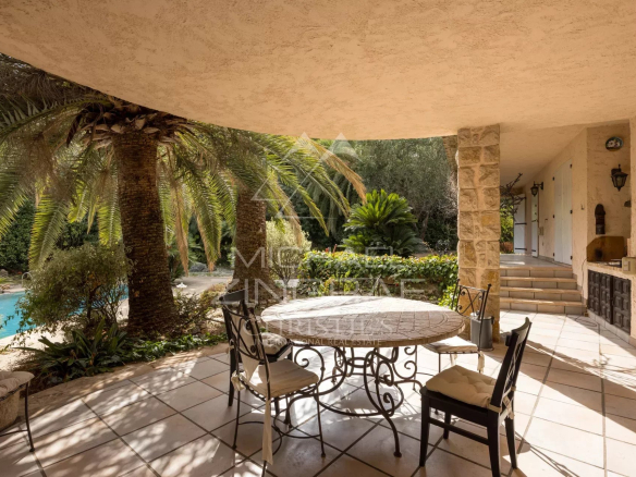 Terrace of a Provençal villa with table and chairs, surrounded by palm trees and greenery in Mougins.
