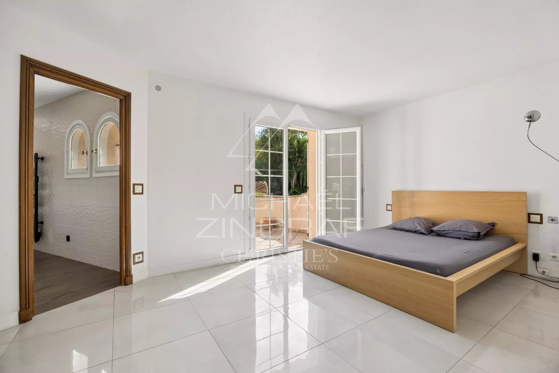 Room in a Provençal villa in Mougins with a wooden bed and access to the outside.