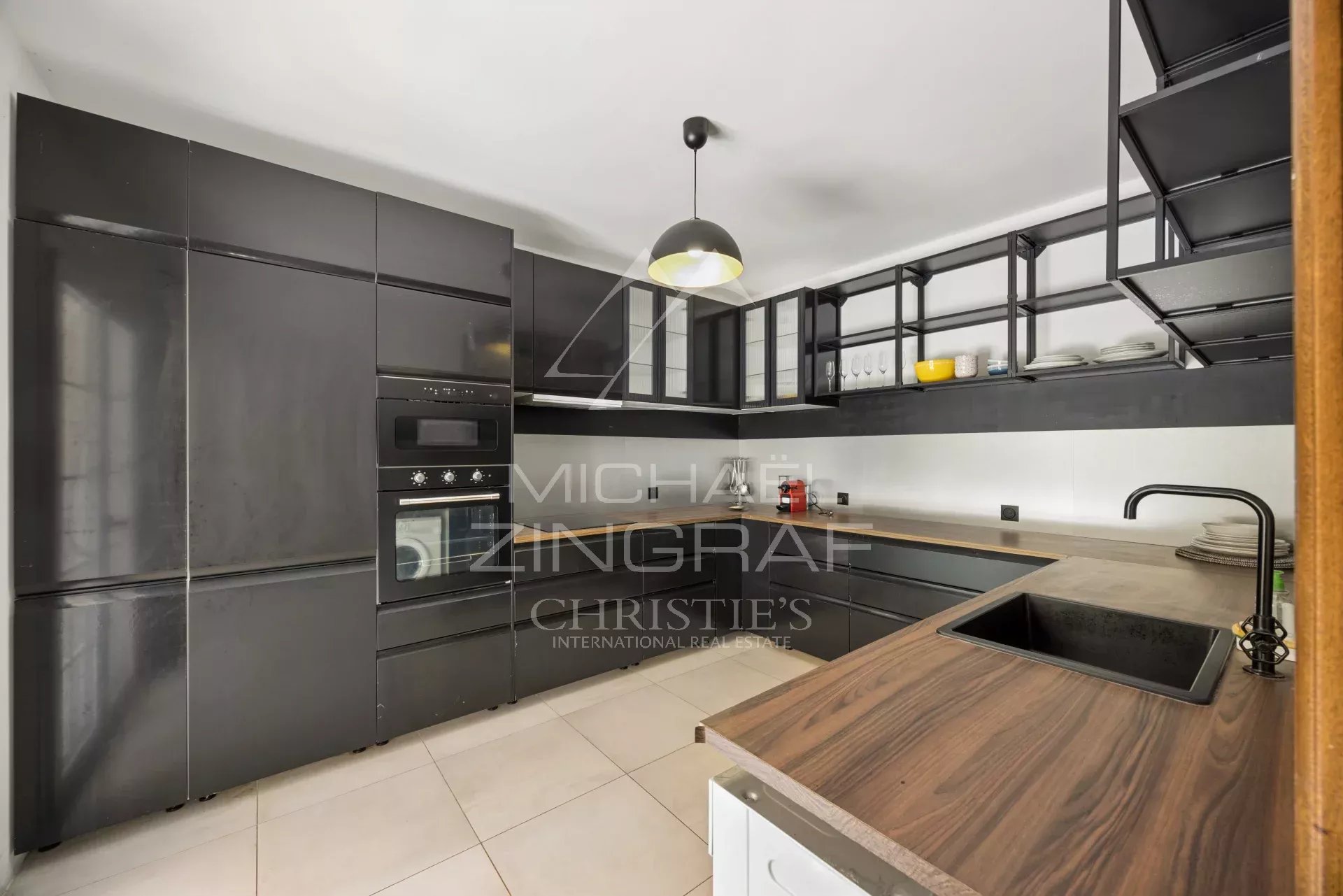 Modern kitchen with black furniture and wooden worktop in a villa in Mougins.