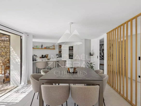 Intérieur d'une villa rénovée avec salle à manger moderne et accès à l'extérieur.