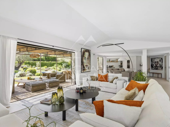 Intérieur d'une villa moderne avec salon lumineux et accès à une terrasse extérieure.
