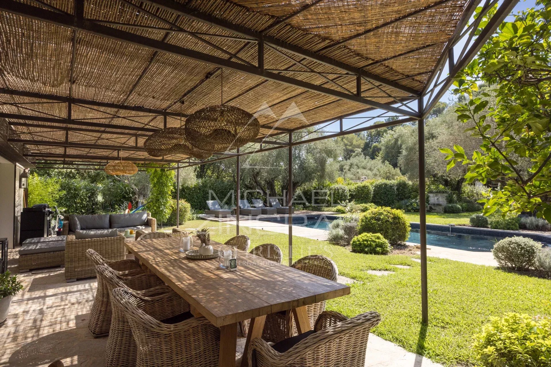 Terrasse en bois avec mobilier, vue sur jardin et piscine dans une villa à Mougins.