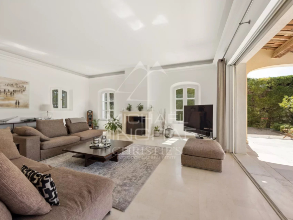 Intérieur d'une villa à Mougins avec un salon lumineux et moderne, cheminée et accès au jardin.