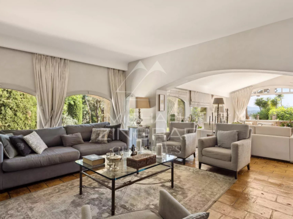 Intérieur d'un mas provençal rénové avec un salon spacieux et lumineux, vue sur les collines.