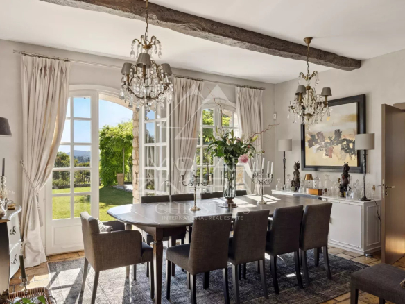 Salle à manger d'un mas provençal rénové avec vue sur les collines, mobilier élégant et lumière naturelle.