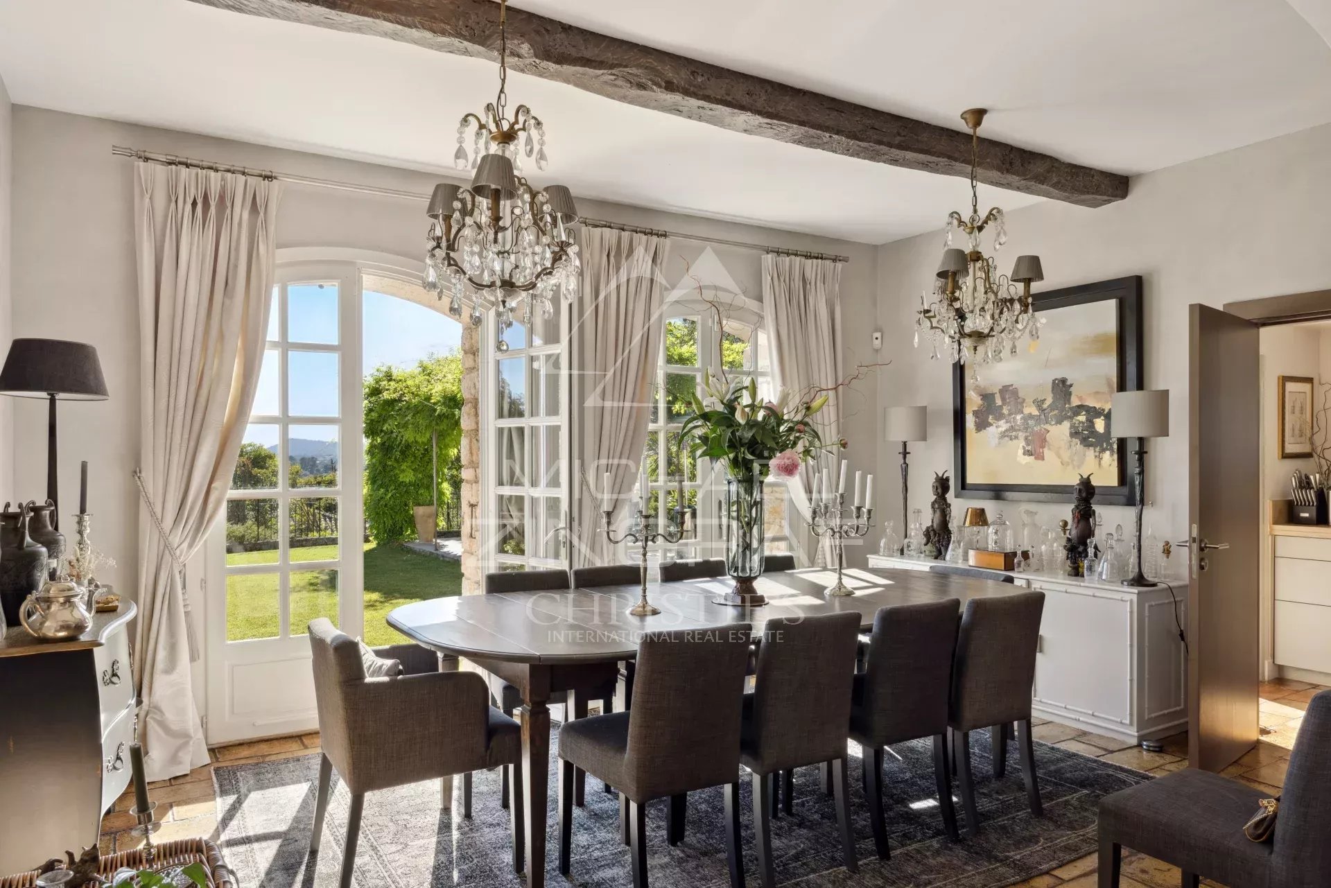 Salle à manger d'un mas provençal rénové avec vue sur les collines, mobilier élégant et lumière naturelle.