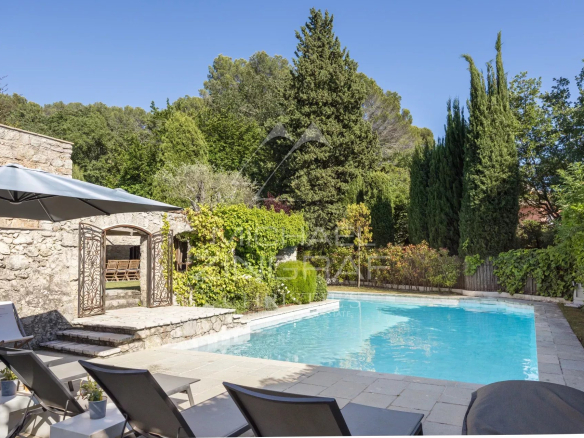 Piscine entourée de verdure et de chaises longues dans un mas provençal rénové.