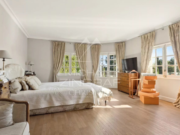 Chambre lumineuse d'un mas provençal rénové avec fenêtres et parquet à Mouans-Sartoux.