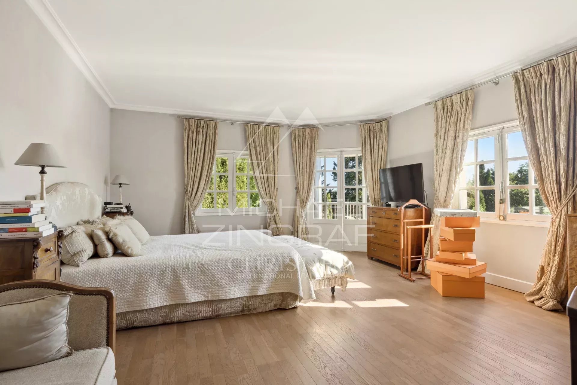 Chambre lumineuse d'un mas provençal rénové avec fenêtres et parquet à Mouans-Sartoux.