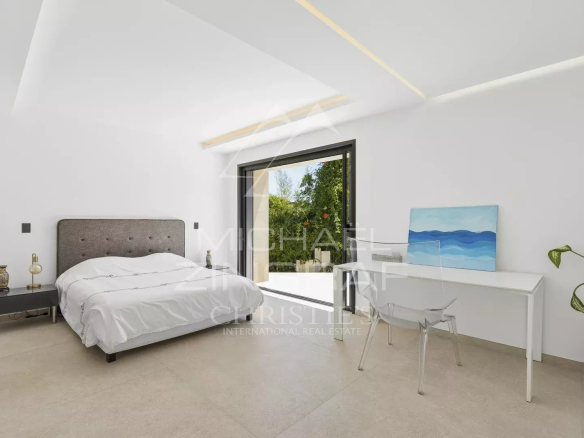 Chambre moderne dans une villa contemporaine à Valbonne, avec lit, bureau et grande fenêtre.