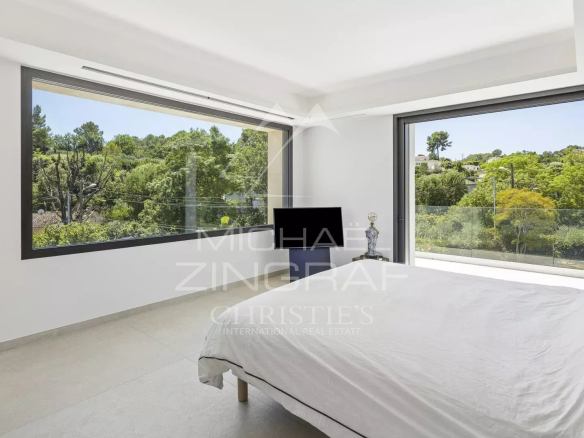 Chambre lumineuse d'une villa contemporaine à Valbonne avec vue sur la verdure.