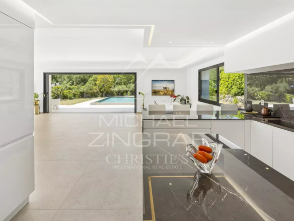 Intérieur d'une villa contemporaine avec cuisine ouverte et vue sur la piscine.