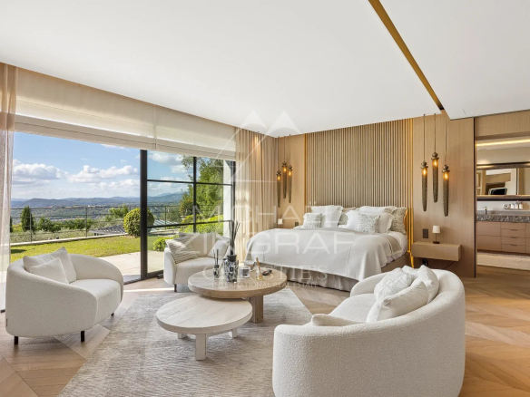 Chambre moderne avec vue panoramique sur les collines et la baie, mobilier élégant, lumière naturelle.