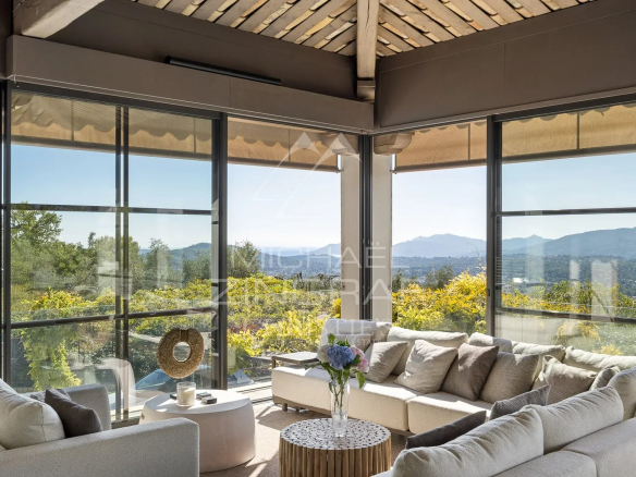 Intérieur d'une bastide moderne avec vue panoramique sur les collines et la baie.