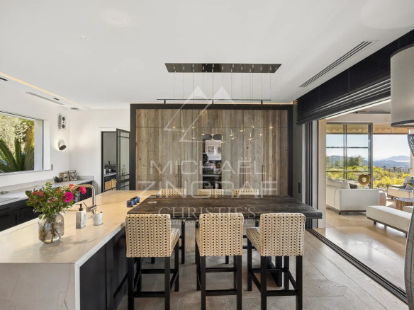 Intérieur d'une bastide moderne avec cuisine ouverte et vue sur les collines.