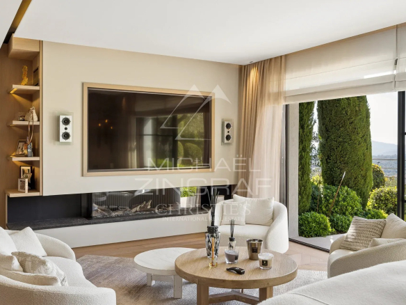 Intérieur d'une bastide moderne avec un salon lumineux et vue sur les collines.