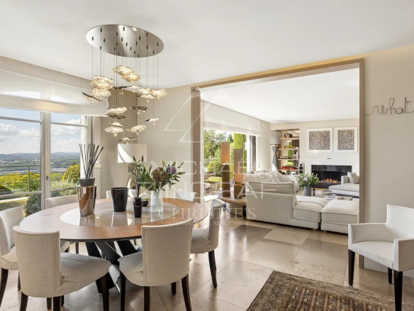 Intérieur d'une bastide moderne avec vue panoramique, table à manger et salon lumineux.