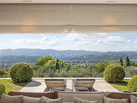 Vue panoramique depuis une bastide moderne avec des collines à l'arrière-plan.