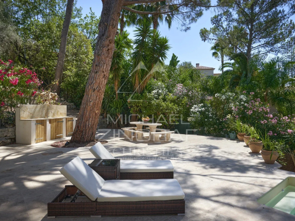 Terrasse d'une villa à Mougins avec chaises longues et plantes fleuries.