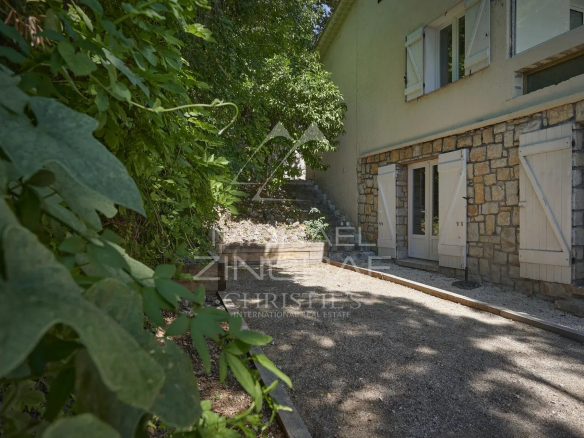 Vue de l'extérieur d'une villa rénovée avec des murs en pierre, entourée de verdure à Mougins.