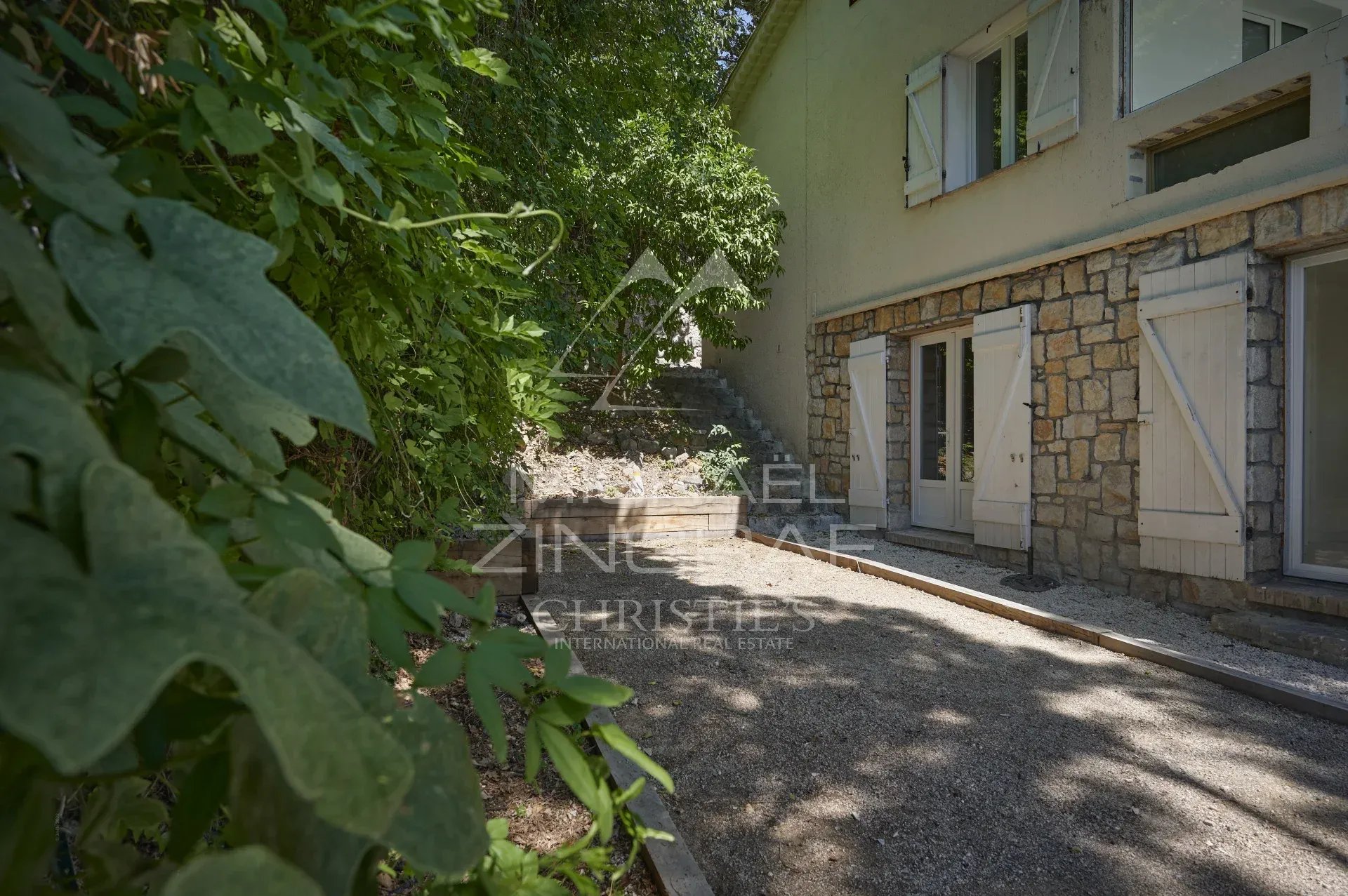 Villa rénovée à Mougins Vue de l'extérieur d'une villa rénovée avec des murs en pierre, entourée de verdure à Mougins.