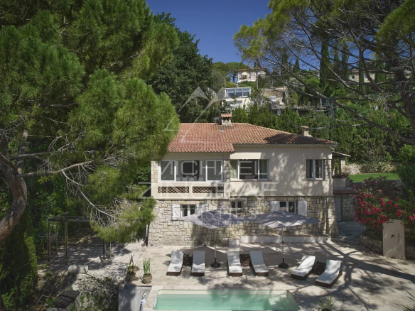 Villa de style provençal avec piscine et terrasse à Mougins, entourée d'arbres.