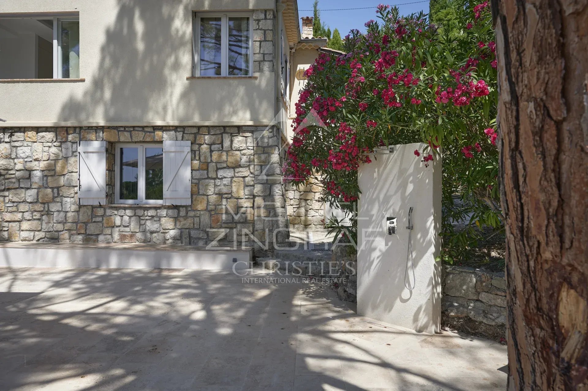 Entrée de villa à Mougins Entrée d'une villa en pierre avec des fleurs et un portail, située à Mougins.